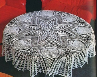 May include: White crocheted tablecloth with a delicate floral design. The tablecloth is round and has a scalloped edge. It is laid on a table in front of two red chairs.