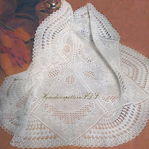 May include: White crocheted baby blanket with a delicate lace pattern. The blanket is folded in half and has a scalloped edge.