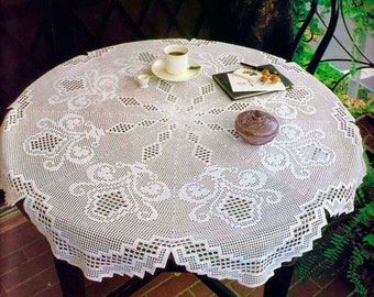 May include: White crocheted tablecloth with a delicate floral pattern, featuring a cup of coffee and a small plate on a round table.