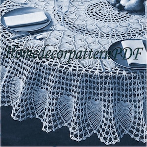 May include: A white crocheted tablecloth with a scalloped edge and a delicate floral pattern. The tablecloth is laid on a table with two place settings and a bowl of fruit.