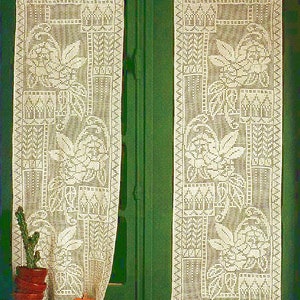 Puede incluir: Dos cortinas blancas de ganchillo con diseños florales cuelgan frente a una puerta verde. Las cortinas están hechas de encaje delicado y presentan un patrón repetitivo de flores y hojas.