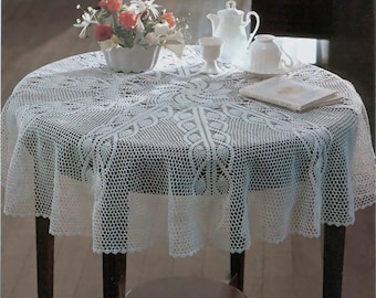 May include: White crocheted tablecloth with a delicate floral pattern, laid on a round wooden table with a vase of flowers and teacups.