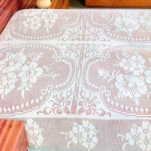 May include: White crocheted bedspread with a floral pattern. The bedspread has a delicate lace trim around the edges.