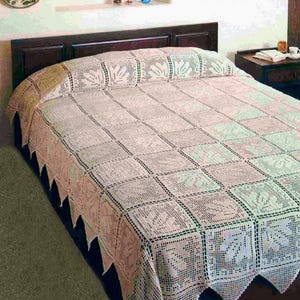 May include: A cream-colored crochet bedspread featuring a repeating square pattern with leaf motifs. The bedspread has a scalloped edge and is draped over a bed with a dark brown headboard. The intricate needlework creates a textured surface.