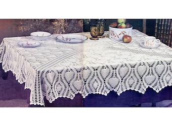 May include: White crocheted tablecloth with a delicate lace pattern and a scalloped edge. The tablecloth is laid on a table with a purple surface and features a central design of repeating hearts.