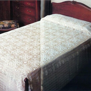 May include: A cream-colored, intricate lace bedspread featuring a repeating geometric pattern with a scalloped edge. The textile is draped over a bed with a dark wood headboard, covering the mattress and extending down the sides with a delicate texture.