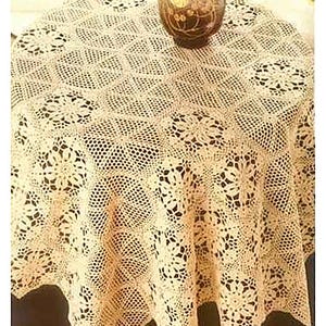 以下が含まれることがあります： クリーム色の、花柄の丸いかぎ針編みのテーブルクロス。テーブルには装飾的な花瓶が置かれています。テーブルクロスは繊細なオープン織りの生地で作られており、ヴィンテージ感を醸し出しています。