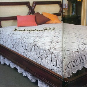 May include: A white crocheted bedspread with a delicate floral pattern. The bedspread is on a wooden bed frame with pillows in shades of orange, brown, and pink.