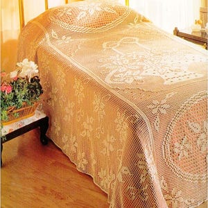Può includere: Un copriletto beige all'uncinetto con motivi floreali copre un letto. L'intricato design presenta un grande motivo floreale al centro e motivi floreali più piccoli. Il copriletto è drappeggiato sul letto, mostrando la sua dettagliata maestria.
