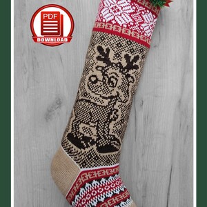 May include: A knitted Christmas stocking with a reindeer design. The stocking features a tan, brown, red, and white color scheme. The top has a white snowflake pattern, and the body has a reindeer motif. The text "CHRISTMAS STOCKING | CHRISTMAS REINDEER PDF KNITTING PATTERN # A21" is at the top.