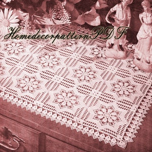 May include: A white crocheted table runner with a square pattern and a scalloped edge. The runner is on a wooden surface.