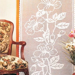 Può includere: Un pannello di tenda bianco all'uncinetto con un design floreale. Il motivo intricato comprende fiori e foglie, creando un'estetica delicata e dettagliata. La tenda è esposta vicino a una sedia vintage con rivestimento floreale.