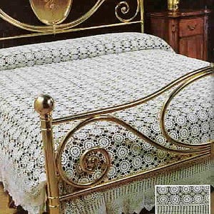 May include: A bed with a gold-coloured metal frame and a white, crocheted bedspread. The bedspread features a detailed floral pattern and a matching skirt. A small inset image shows a close-up of the crochet design.