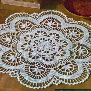 May include: White crocheted doily with a delicate floral pattern. The doily is circular and has a scalloped edge.