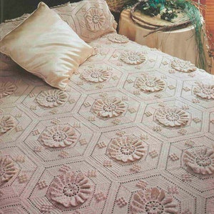 May include: A crocheted bedspread with a delicate floral pattern in shades of pink and white. The bedspread is made with a repeating hexagonal design, creating a beautiful and intricate texture.