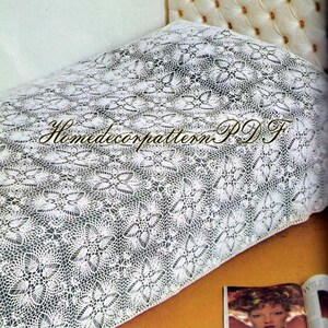 Könnte beinhalten: Eine weiße Häkel-Tagesdecke mit einem sich wiederholenden Blumenmuster. Der Text "HomedecorpatternPDF" ist über die Mitte des Stoffes gelegt. Die Tagesdecke liegt auf einem Bett mit gepolstertem Kopfteil, daneben liegt eine Zeitschrift.