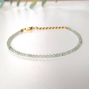 May include: A delicate bracelet made with light green beads and a gold chain clasp.
