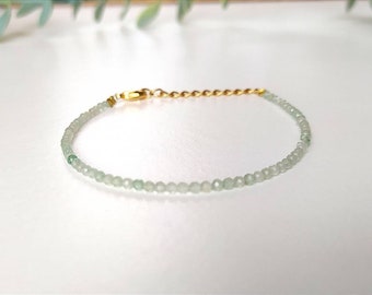 May include: A delicate bracelet made with light green beads and a gold chain clasp.