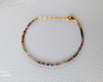 May include: A delicate bracelet made with small, colorful gemstones. The bracelet features a gold clasp and is strung with pink, green, and blue beads.