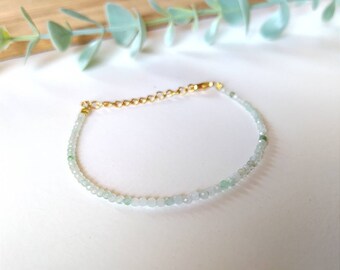 May include: A delicate bracelet made with light green and white beads, accented with a gold chain clasp.