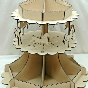 May include: A two-tiered carousel display stand constructed from light beige wood. The structure features scalloped edges on each tier and includes several flat, laser-cut horse silhouettes positioned between the levels of the stand.