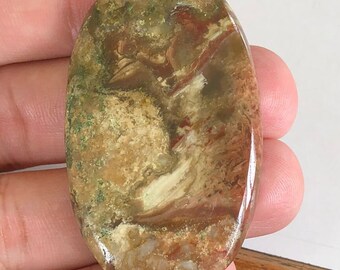 May include: A smooth, oval-shaped cabochon of green, brown, and white agate. The stone has a swirling pattern of colors and a polished finish.
