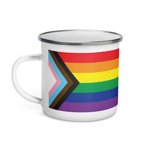May include: White enamel mug with a rainbow pride flag design. The flag includes the traditional rainbow colors, plus black, brown, light blue, and pink stripes.