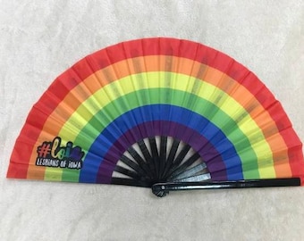 May include: A rainbow-colored hand fan with a black handle. The fan has the text "#loia Lesbians of Iowa" printed on it.