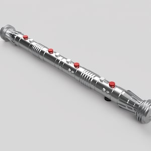 May include: A silver lightsaber hilt with red buttons. The hilt has a textured surface and a rounded end.