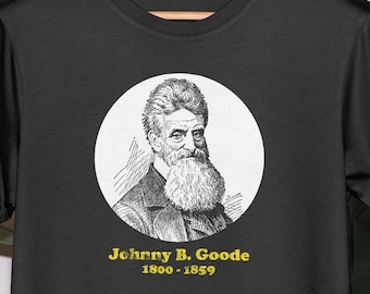 Pode incluir: Camiseta preta com um círculo branco contendo uma ilustração em preto e branco de Johnny B. Goode. O texto "Johnny B. Goode 1800-1859" é impresso em amarelo abaixo do círculo.