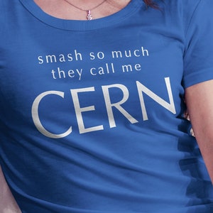 May include: A royal blue t-shirt with the text "smash so much they call me CERN" in white. The shirt has a scoop neck and short sleeves. A small logo is visible in the upper right corner.