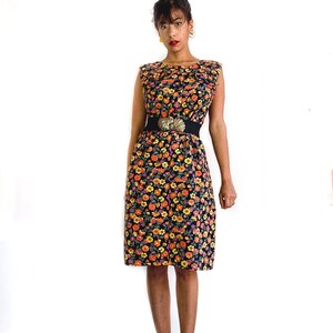 May include: A sleeveless black dress with a floral print in shades of orange, yellow, and pink. The dress has a black belt with a gold buckle.