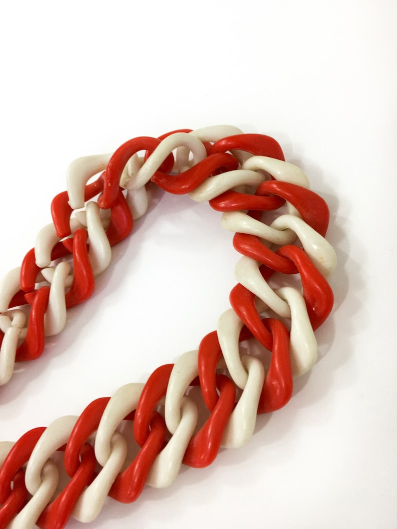 May include: A red and white plastic chain necklace. The chain is made of large, chunky links.
