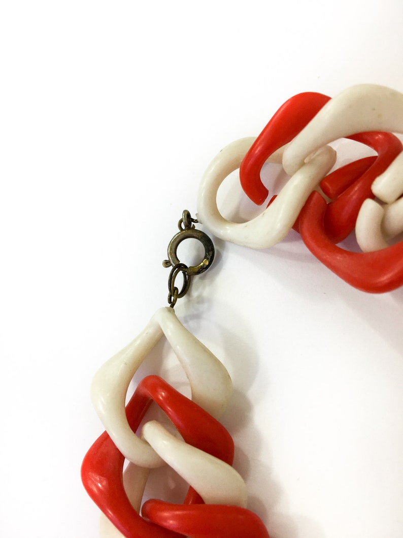 May include: A red and white plastic chain necklace with a gold-toned clasp.