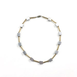 May include: A silver and gold necklace with square-shaped beads. The necklace is made of metal and has a simple design.