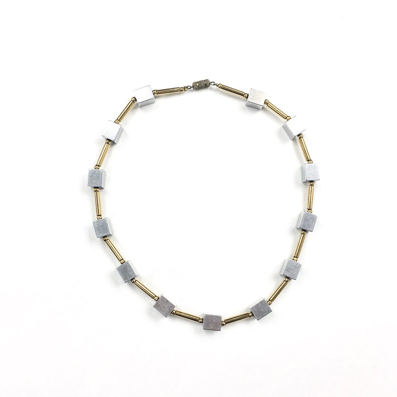 May include: A silver and gold necklace with square-shaped beads. The necklace is made of metal and has a simple design.