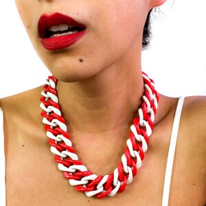 May include: A red and white chunky chain necklace. The necklace is made of plastic and has a bold, geometric design.