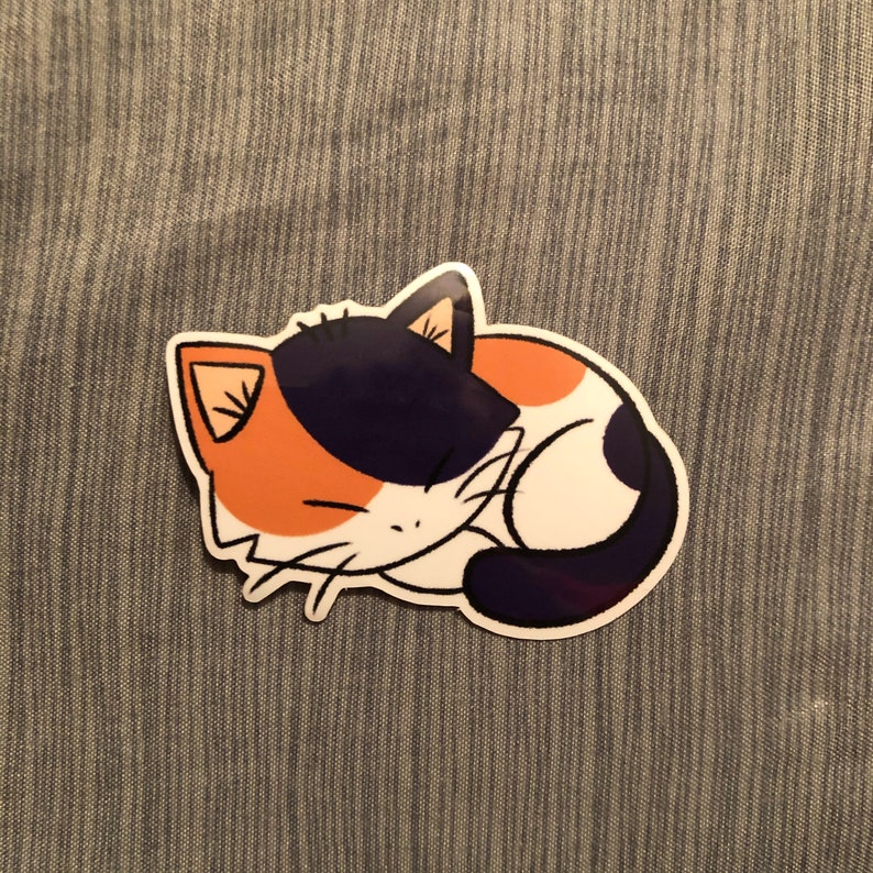 May include: A sticker featuring a cartoon calico cat curled up asleep. The cat has orange, black, and white markings, with a white outline. The sticker is on a gray textured background.