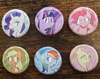 Può includere: Sei bottoni rotondi con illustrazioni colorate dei personaggi di My Little Pony. Ogni bottone presenta un design di pony diverso, tra cui Rarity, Twilight Sparkle, Pinkie Pie, Applejack, Rainbow Dash e Fluttershy.