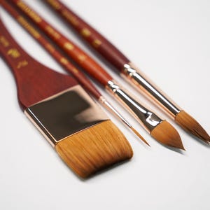 May include: Four paint brushes with wooden handles and gold metal ferrules. The brushes have different sizes and shapes of bristles.