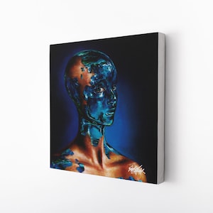 May include: A canvas print depicting a surreal portrait of a person with a metallic blue face and exposed skin. The artwork has a dark blue background and is mounted on a white wall. The artist's signature is visible.
