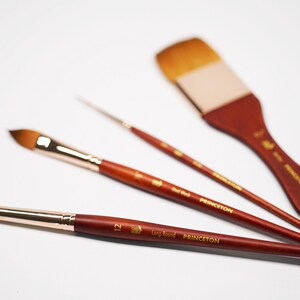 May include: Three paint brushes with wooden handles and gold lettering. The brushes are labeled "Princeton" and "Long Handle". The largest brush has a flat, rectangular head. The other two brushes have round heads.