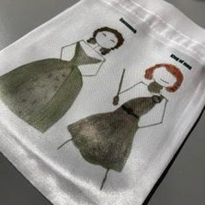 May include: White satin drawstring bag with a green and gold print of two stick figures wearing dresses. The text "Downton Abbey" and "King of Spain" is printed on the bag.