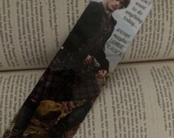 May include: A bookmark featuring a character from the Outlander series. The bookmark is a close-up of the character's face and torso. The character is wearing a kilt and holding a sword. The text on the bookmark reads "I don't want to do anything today".
