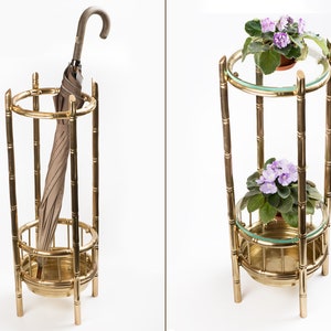 May include: A brass umbrella stand with a brown umbrella and a brass plant stand with two levels, each holding a potted plant with purple flowers and green leaves. The stands have a bamboo-like design.
