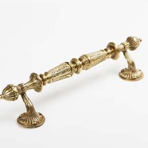 Può includere: Una maniglia per porta dorata con dettagli decorativi e un pomo decorativo su ciascuna estremità.