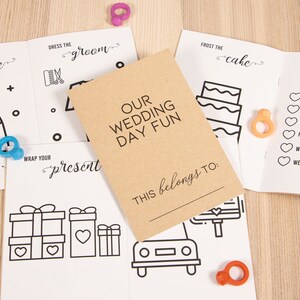 May include: A set of six printable wedding day activity cards with a brown cover that says "Our Wedding Day Fun" and "This belongs to:". The cards include activities like "Dress the Bride", "Dress the Groom", "Wrap Your Present", "Frost the Cake", and "Wedding Day Spy".