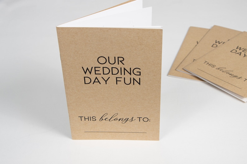 May include: A brown paper booklet with the text "OUR WEDDING DAY FUN" and "THIS belongs TO:" printed on the front cover.