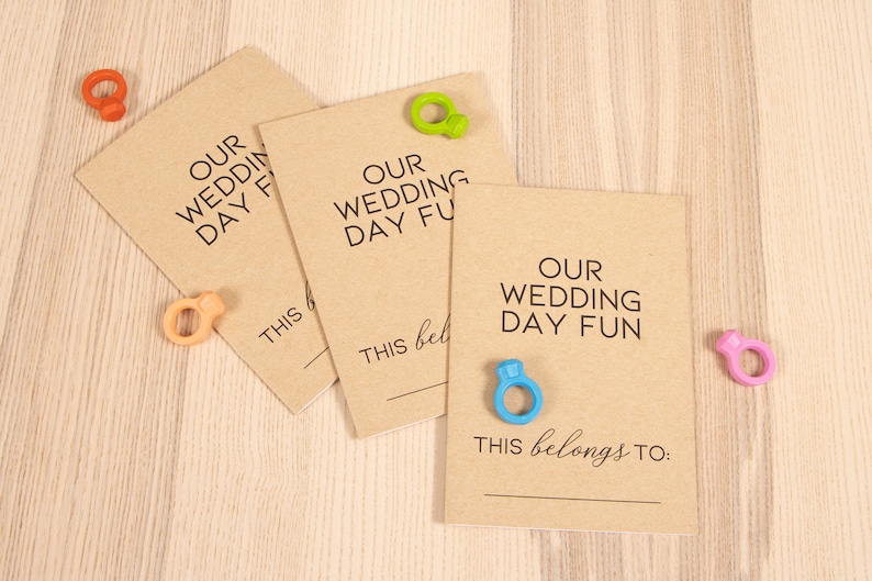 May include: Three brown cards with the text "Our Wedding Day Fun" and a blank line for writing. Each card has a colorful ring attached to it.
