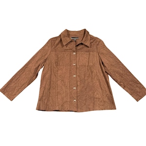 May include: A brown button-up jacket with a textured pattern. The jacket has a collared neckline, two chest pockets, and long sleeves. The buttons are silver-colored. The jacket is laid flat on a white surface.